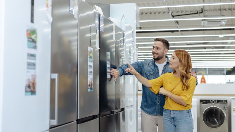 A couple shopping for refrigerators at an appliance store