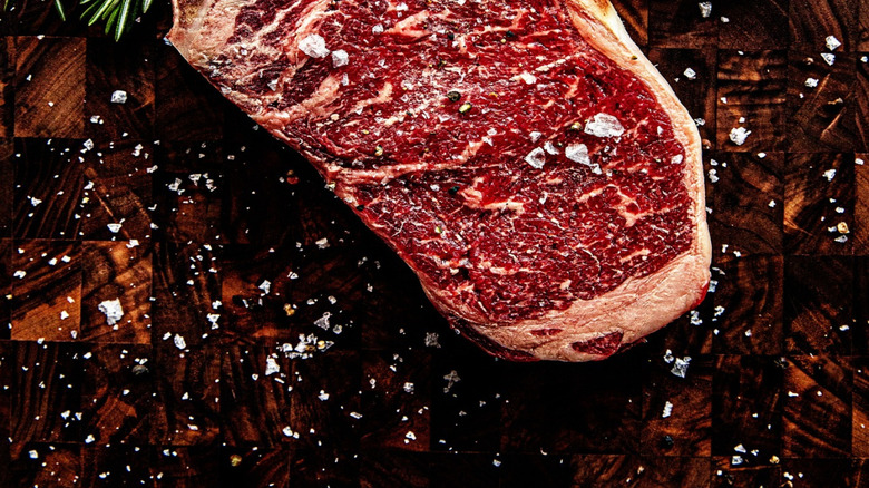 Oak Steakhouse uncooked Dry-Aged KC Strip with salt and pepper seasoning.