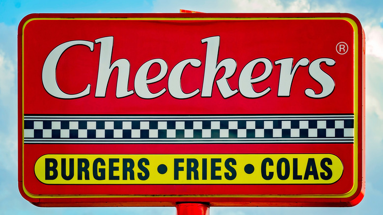A Checkers sign stands against a blue sky