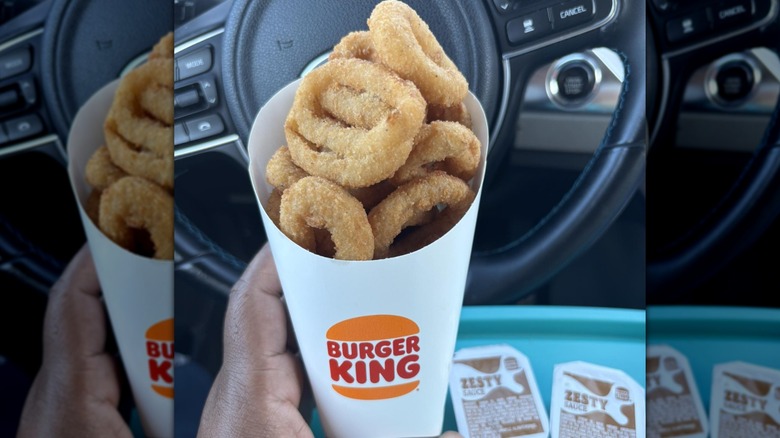 Person holding up an order of Burger King onion rings