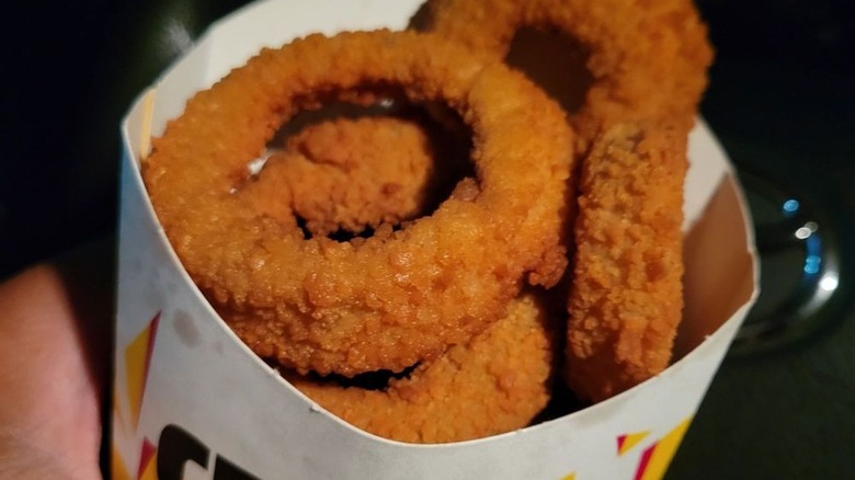 Person holding an order of onion rings from Carl's Jr