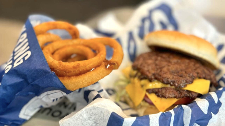 An order of onion rings from Culver's sitting on a tray next to a burger