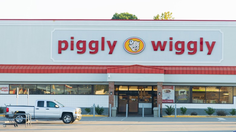 The exterior of Piggly Wiggly with a pick up truck passing
