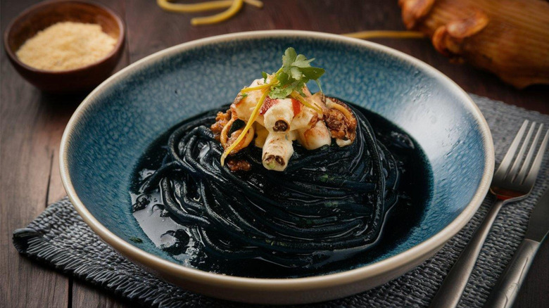 Squid ink pasta with seafood in a blue bowl