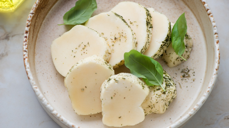 Ceramic plate with sliced Halloumi cheese and fresh basil leaves