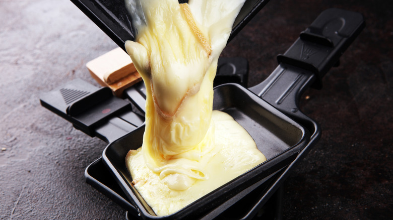 Melted Raclette cheese being poured form individual skillet to another