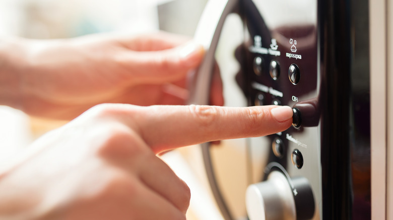 pressing buttons on a microwave