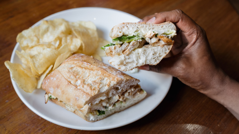person holding a sandwich made with caesar dressing