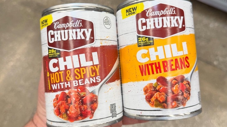 A customer holds up two cans of Campbell's chunky chili