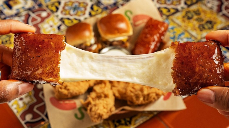 Hands pulling apart Fried Mozzarella at Chili's restaurant.