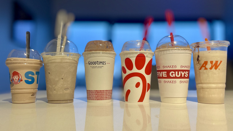Various chocolate shakes from fast food restaurants lined up on a table