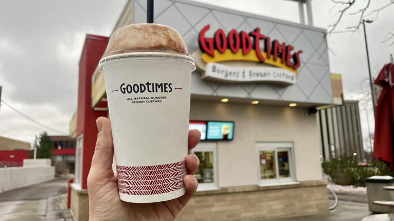 A hand holds up a Good Times chocolate shake