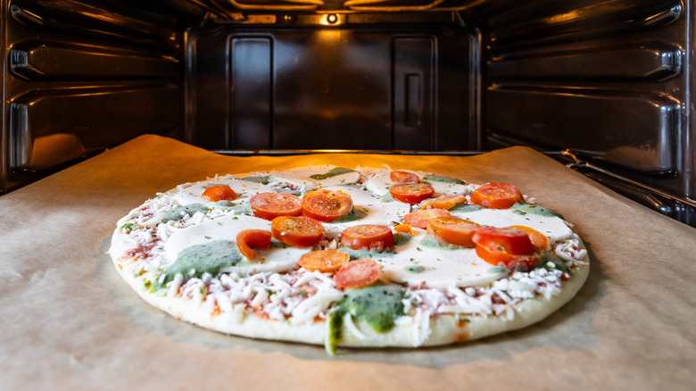 A frozen margherita pizza with tomatoes and basil in the oven