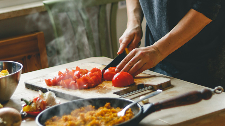 Cook slicing tomatoes on a wooden cutting board