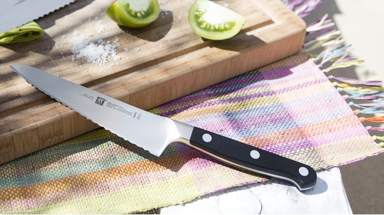 Zwilling Pro 5.5 inch serrated prep knif resting on wooden cutting board