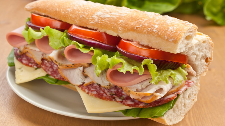 A stuffed half of a sub is filled with meats, cheese, and toppings
