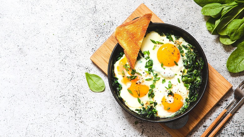 Fried eggs and greens in a bowl with toast