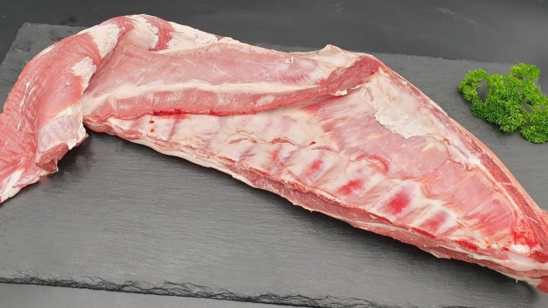 A raw lamb breast on a wooden cutting board