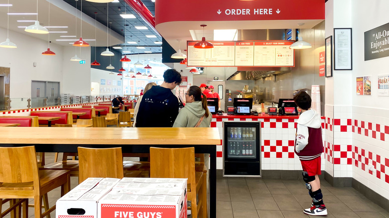 Customers inside a Five Guys showing its red and white interior