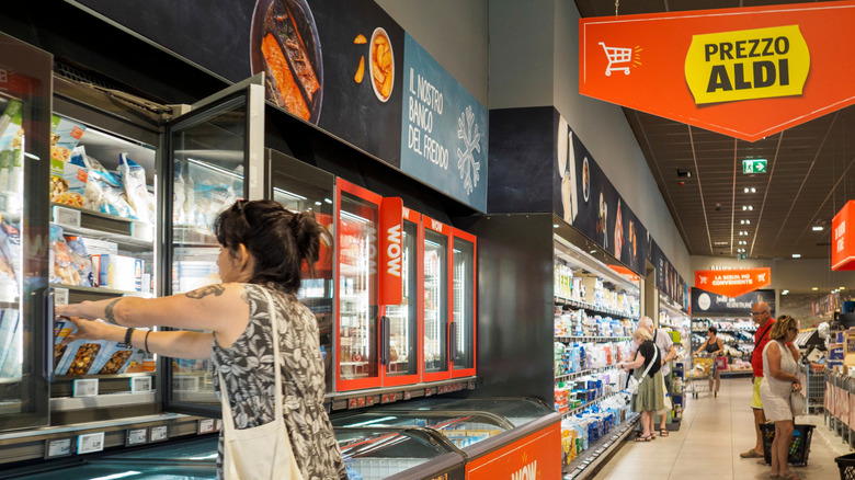 Shopper getting items from frozen food aisle at Aldi