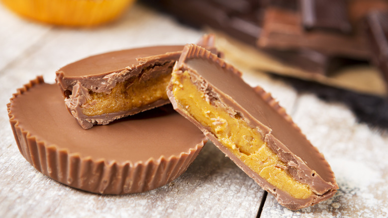 A halved peanut butter cup leans on a full peanut butter cup.