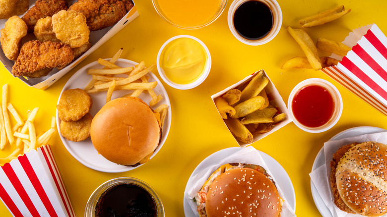A selection of various types of fast food, including chicken nuggets, tenders, burgers, french fries, drinks, and dips