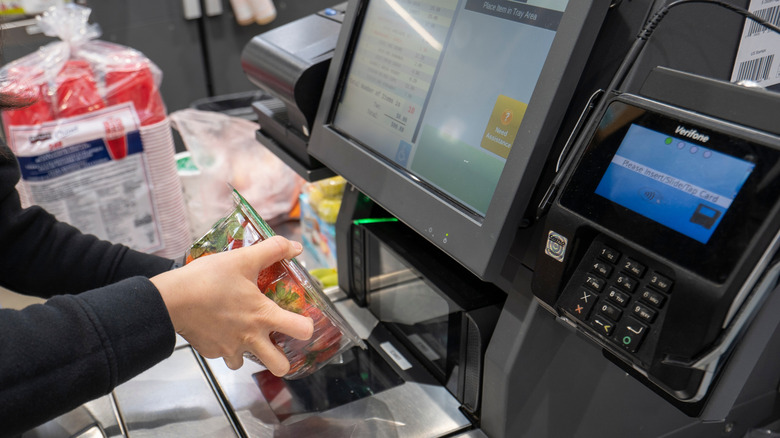 A person scanning items at a Costco self checkout area
