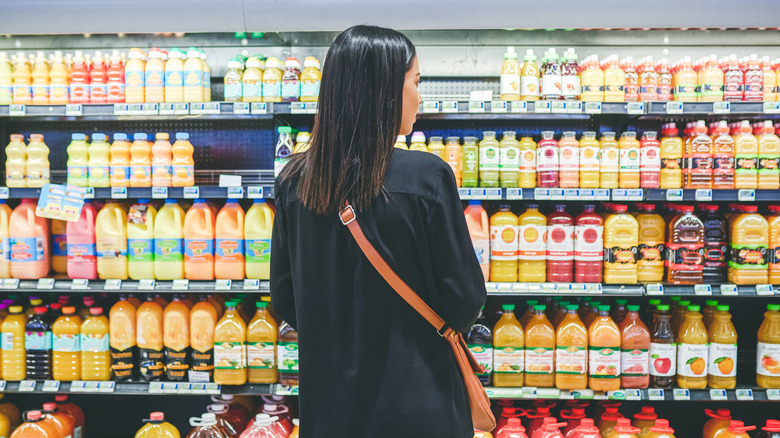 person grocery shopping in the juice aisle