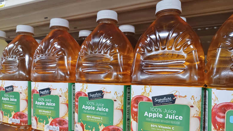 Bottles of Signature SELECT apple juice sit on a grocery store shelf