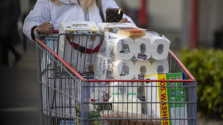 A close up of a Costco shopper pushing a full cart out into the parking lot