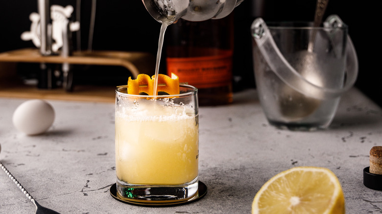 Pouring whiskey sour into glass