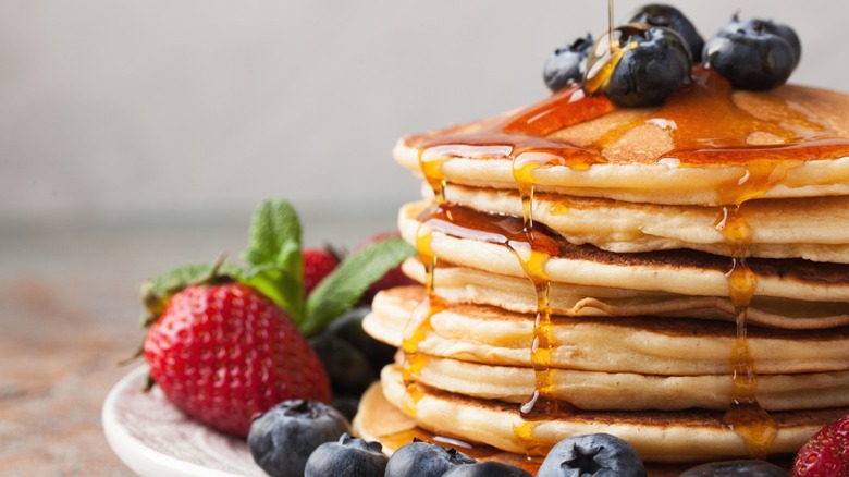 Stack of pancakes topped with blueberries and strawberries 