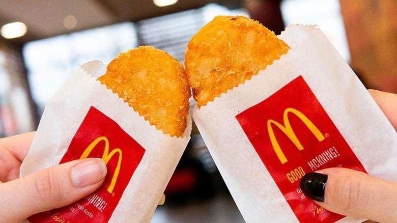 Two hands hold up two hash browns from McDonald's.