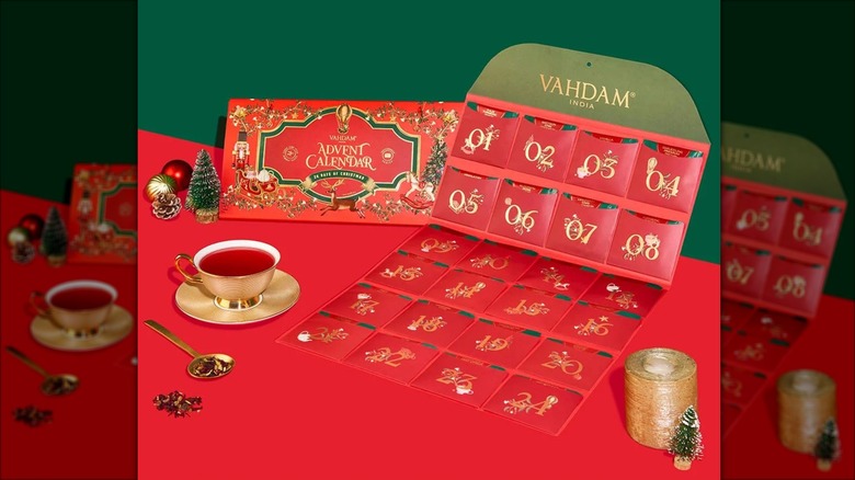 A VAHDAM India tea advent calendar sits on a festive table near a tea-filled gold teacup and saucer