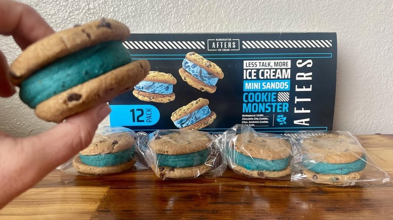 Hand holding an Afters Ice Cream Cookie Monster Ice Cream Sando with wrapped ones and the box in the background