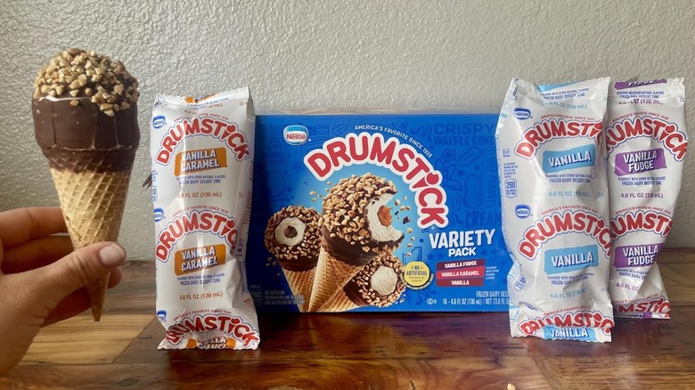 Hand holding a Nestlé Drumstick with Variety Pack box and wrapped flavors on display