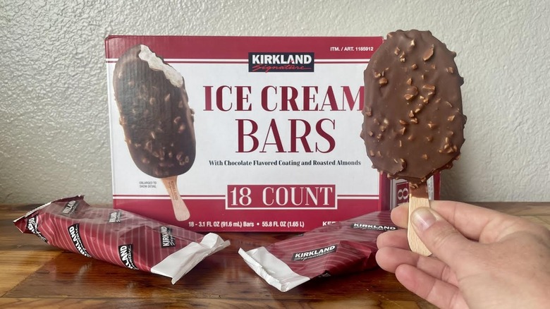 Hand holding unwrapped Kirkland Signature Ice Cream Bar in front of the packaging