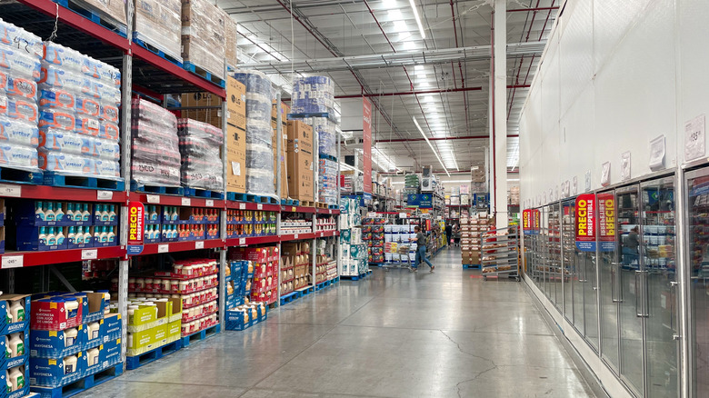 A person at the far end of a long Sam's Club aisle pushes their cart