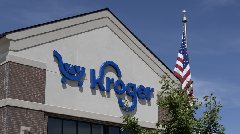 The exterior of a Kroger store with an American Flag