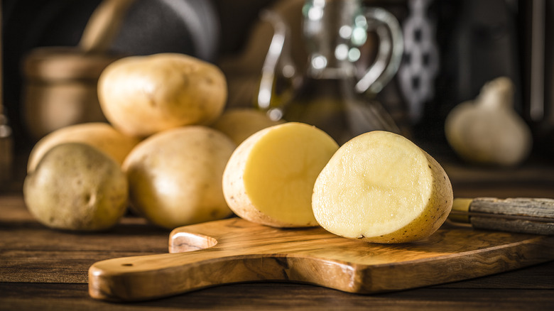 Potato cut in half on wooden cutting board