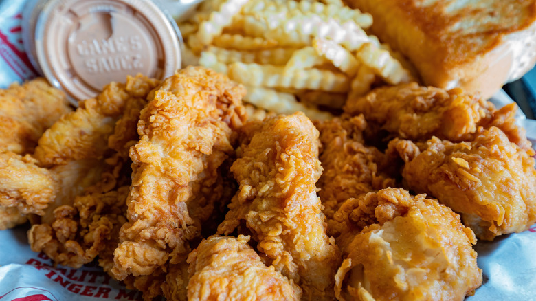 Basket of Raising Cane's chicken fingers with fries and Cane's sauce