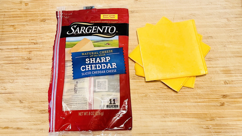 Package of Sargento Sharp Cheddar Cheese with a quartered grilled cheese sandwich