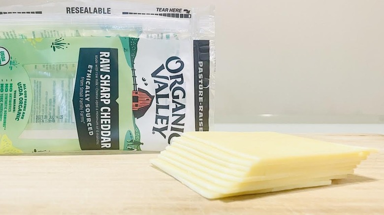 Stack of sliced Organic Valley Raw Sharp Cheddar Cheese with packaging