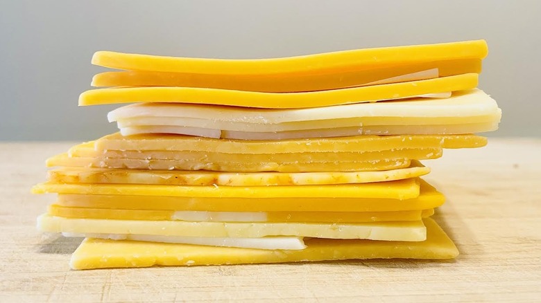 Stack of various types of sliced cheddar cheese