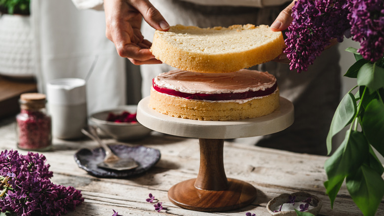 Chef assembling a layered cake on cake stand