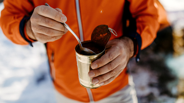 man eating from a can