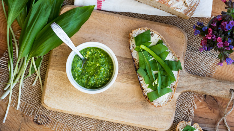 Bowl of pesto and piece of bread on a cutting board