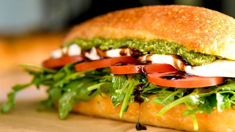 sandwich with tomato, mozzarella, greens, and pesto