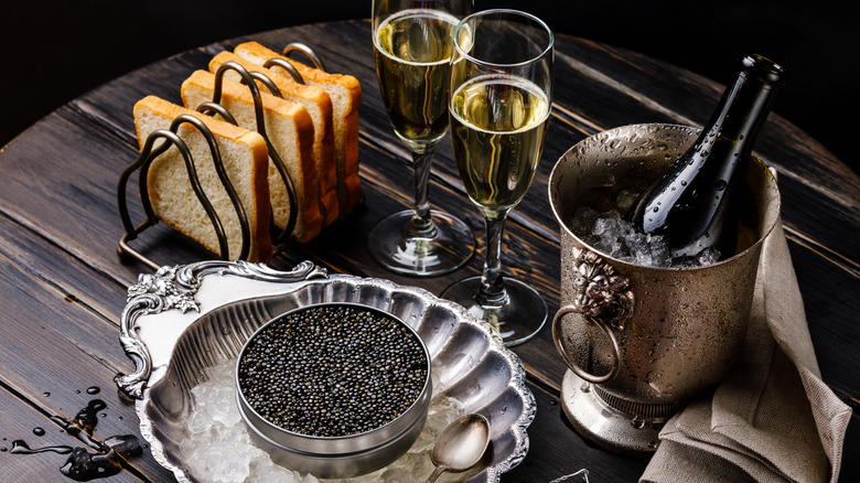 Caviar with toast, glasses of Champagne, and a bottle of Champagne in a metal bucket with ice