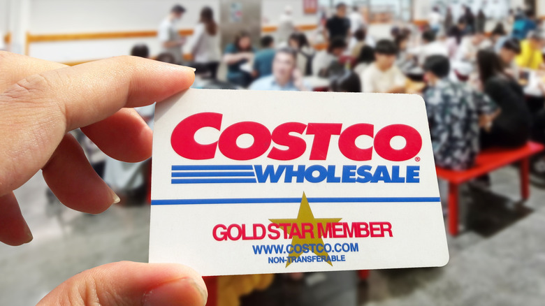 Hand holding a Costco membership card in-store.
